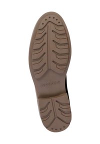 Semelle de chaussure en caoutchouc présentant de multiples rainures texturées pour une meilleure adhérence, de couleur beige avec un détail de marque subtil "REDSKINS" près du talon.