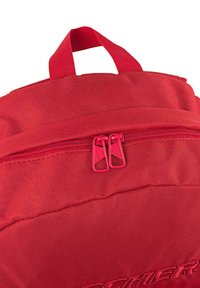 Mochila de tela roja con asa superior, cierre de cremallera dual y superficie texturizada. Bordado del logotipo destacado en el panel frontal.