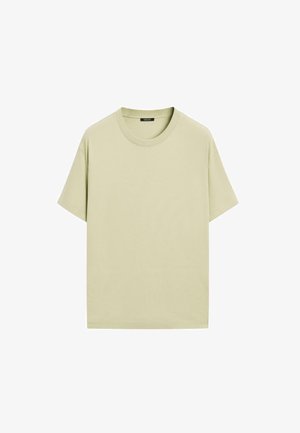 Jasnozielona bawełniana koszulka z krótkim rękawem, okrągłym dekoltem i luźnym fasonem. Prosta, jednolita kolorystyka, bez widocznych wzorów czy zdobień.