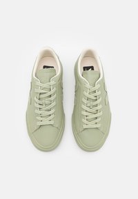 Zapatillas de cuero verde claro con una textura suave, que presentan una puntera redondeada, cordones planos y sutiles detalles de acento.