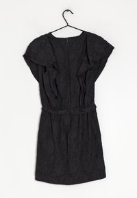 Robe noire avec des manches courtes flottantes et une taille cintrée. Présente un motif floral texturé et une fermeture éclair au dos.