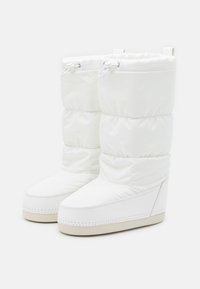 Bottes de neige blanches rembourrées avec un extérieur lisse, tige haute et talon compensé. Dotées d'un cordon élastique en haut et d'une semelle texturée contrastante.