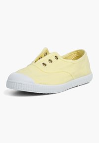Sznurowane buty z płótna w jasnym żółtym kolorze z białą gumową podeszwą i trzema metalowymi oczkami. Okrągły czubek i fakturowana cholewka.