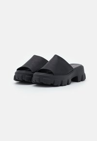Sandalias de plataforma abiertas en la parte delantera de color negro, con un upper suave y una suela gruesa y estriada para mayor agarre. Fabricadas con material duradero y un acabado mate.
