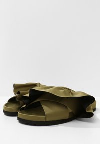 Sandali in tessuto verde oliva con due strati di volants, design open-toe e suola nera texturizzata per una maggiore aderenza.