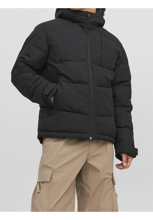 Svart puffjacka med huva, med dragkedja, ribbade muddar och ett quiltat mönster. Bärs över khakifärgade cargobyxor.