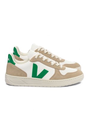 Zapatillas blancas y beige con un logo verde, que cuentan con texturas de ante y malla, puntera redonda y suela plana de goma.