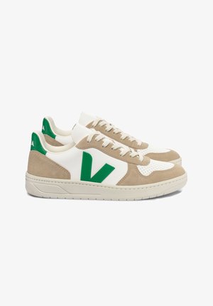 Zapatillas blancas y beige con un logo verde, que cuentan con texturas de ante y malla, puntera redonda y suela plana de goma.