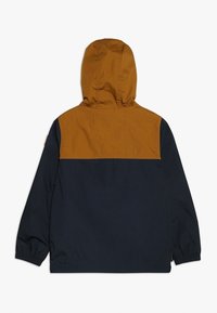 Giacca con cappuccio, con la parte superiore marrone e la parte inferiore blu scuro. Realizzata in tessuto leggero, presenta polsini elasticizzati e un design pulito.