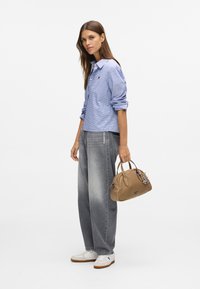 Blå og hvit rutet skjorte, grå vide jeans, hvite joggesko, og en brun håndveske med en charm, med en glatt tekstur.