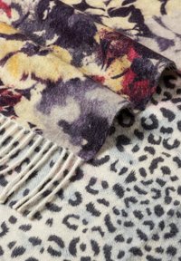 Bunte Schal aus weichem Stoff mit floralem und Leopardenmuster, mit fransigen Kanten und glatter Textur.