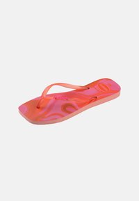 Tongs en caoutchouc à motifs rose et orange avec des brides fines et une semelle texturée, vue en angle sur un fond uni.