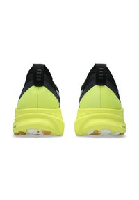 Scarpe sportive nere e gialle neon con una suola arrotondata, tomaia con texture e linguette sul tallone, caratterizzate da audaci segmenti di colore contrastante.
