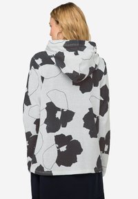 Witte hoodie met een textuurpatroon van zwarte bloemen en omtrekken. Beschikt over een ontspannen snit en zichtbare stiksels.