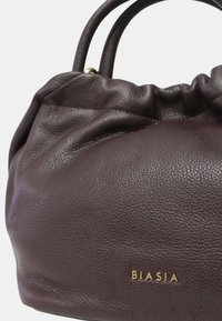 Borsa a tracolla in pelle bordeaux con design arricciato sulla parte superiore, caratterizzata da una texture liscia e da un logo dorato "BIASIA" sul davanti.