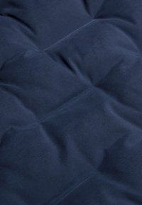 Marinblå vadderad tyg med en slät textur, med en kviltad design och synliga sömmar som skapar en mjuk och inbjudande look.