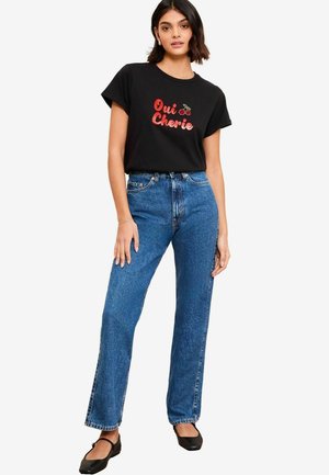 Black t-shirt with "Oui Cherie" text and cherry graphic, paired with light blue high-waisted straight-leg jeans and black flats.