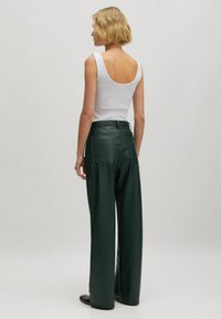 Groene faux leren wijde broek met hoge taille, twee achterzakken en een zachte textuur, gecombineerd met een witte tanktop.