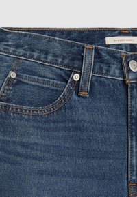 Niebieskie, luźne szorty z denimu z zamkiem błyskawicznym i zapięciem na guzik, wieloma kieszeniami, kontrastującym pomarańczowym przeszyciami oraz fakturą materiału.