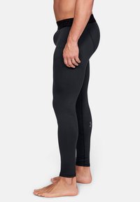 Schwarze sportliche Leggings aus glattem, dehnbarem Material mit einem strukturierten schwarzen Bund und einem dezenten Logo-Detail an der Unterschenkel.