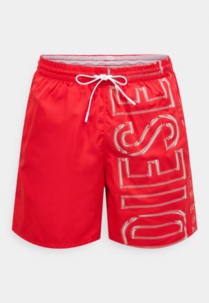 Sarkanas peldēšanas šorti no gluda auduma, ar baltu aukliņu un spīdīgu sudraba tekstu sānos. Garums līdz viduscelim un vienkāršs aizmugure.