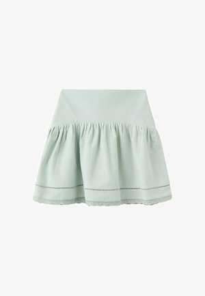 Jupe taille haute vert clair avec tissu froncé et bordure en dentelle le long de l'ourlet, présentée sur un fond blanc.