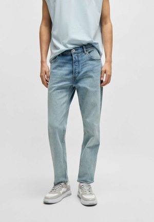 Jeans in denim azzurro chiaro con vestibilità dritta, design a cinque tasche, passanti per cintura e cuciture a contrasto. Indossati con sneakers neutre.