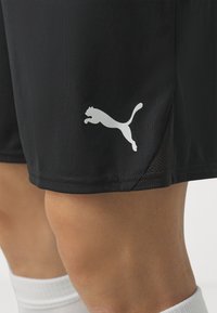 Svarta träningsshorts av glattyg med vita nätdetaljer och en tydlig vit Puma-logotyp vid vänstra fållen.