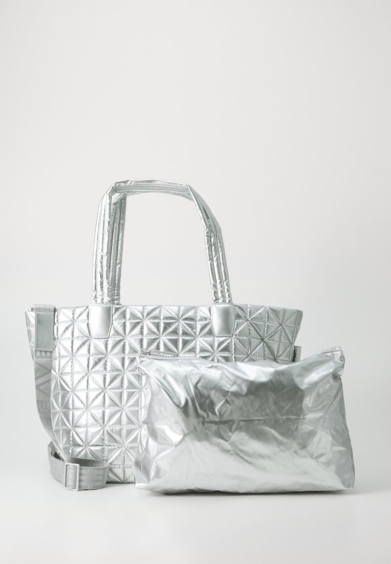 Sølv totebag med kviltet geometrisk mønster, med to korte håndtak og en avtakbar glinsende tørk. Glatt metallisk tekstur.