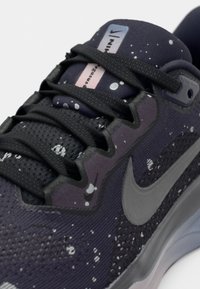 Dark purple Nike sneaker with black laces, light speckled pattern, and silver swoosh logo near the sole and tongue.