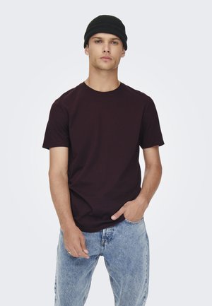 T-shirt courte marron associé à un jean en denim bleu clair. Un bonnet tricoté noir complète le look décontracté. Design simple, sans motifs.