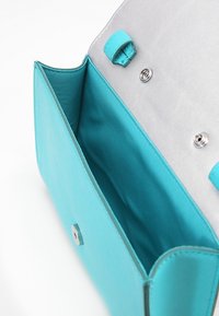 Turkusowa torebka syntetyczna z srebrnym wnętrzem, z zapięciem na magnes i gładką teksturą. Otwarta, pokazująca wewnętrzne wykończenie.