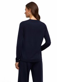 Granatowa bluzka z długim rękawem wykonana z miękkiego materiału, z okrągłym dekoltem i prążkowaną strukturą. Tył ma prosty design bez wzorów.