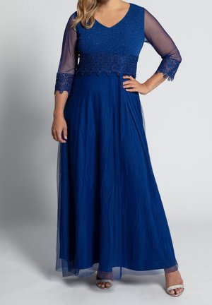 Langes blaues Kleid mit V-Ausschnitt, transparenten Ärmeln, bestickter Taille und fließendem Rock. Funkelnde Akzente betonen das Design des Oberteils.
