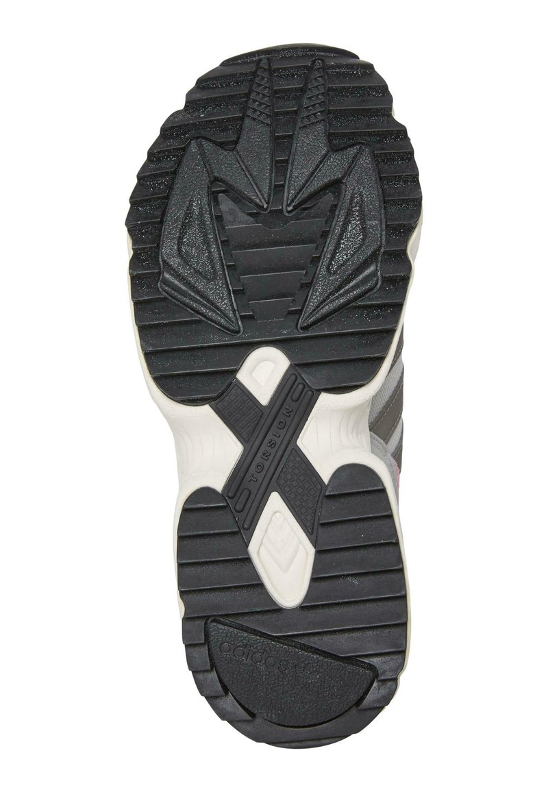 Suola di sneakers in gomma nera con motivo testurizzato, caratterizzata da rilievi e scanalature distintive per una presa migliore, e una intersuola bianca con dettaglio del logo.