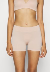 Light pink seamless shorts with a wide elastic waistband, made from a soft, stretchy material, designed for comfort and ease of movement.
