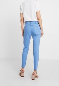 Ljusblå skräddarsydda byxor med smal passform, slät front, sidofickor och bakfickor. Bärs med en kortärmad vit topp och klackar.