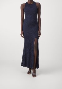 Abito halter in pizzo blu navy con corpetto aderente e gonna lunga caratterizzata da uno spacco laterale. Tessuto morbido con dettagli floreali.