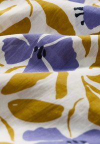 Tissut multicolor cu modele florale mari în nuanțe de purpuriu și galben muștar pe un fundal alb, având o textură netedă și moale.