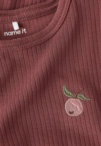 Rebrasti bordo majica s okruglim izrezom i ukrasnim vezom breskvastog motiva koji sadrži ružičasto voće i zelene listove.