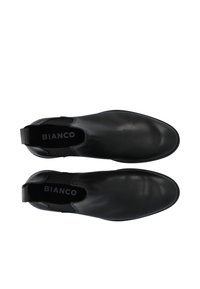 Botines de cuero negro con textura suave, paneles laterales elásticos y una lengüeta en el talón para facilitar su uso. Marca visible en el interior.