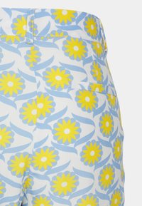 Calções com padrão floral apresentando um design em azul e branco com margaridas amarelas e espirais verdes. Inclui um bolso traseiro e detalhe em botão.