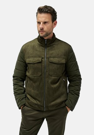 Chaqueta verde oliva con textura suave, cierre de cremallera en la parte delantera, cuello alto y dos bolsillos en el pecho. Presenta mangas acolchadas y voluminosas.