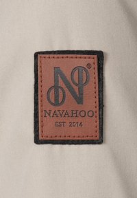 Brown leather tag with black embossed text "NAVAHOO" and "EST 2014," bordered by gray fabric and a black felt edge.