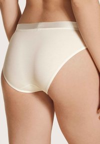 Beige Baumwollunterhosen mit einem weichen Elastikbund, die eine glatte Textur und ein Design mit voller Abdeckung aufweisen, von hinten präsentiert.