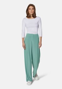 Lightweight, mint green wide-leg pants with a high waist, pleats at the front, and a single button closure, paired with a white long-sleeve top.