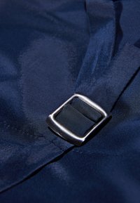 Marineblauer Stoff mit einer glatten Textur und einer Metallschnalle. Die Schnalle ist rechteckig mit einer silbernen Ausführung und ist an einem Riemen befestigt.