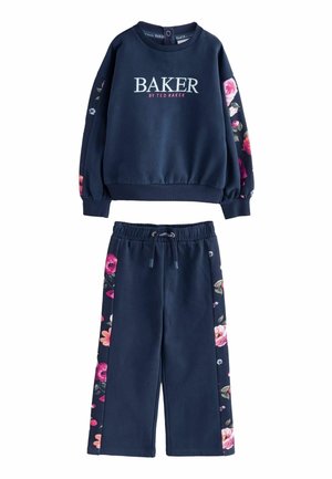Ensemble de sweat-shirt et pantalon bleu marine. Le sweat-shirt arbore le logo "BAKER" ; les manches sont à motifs floraux. Le pantalon présente des accents floraux sur les côtés et un cordon de serrage.