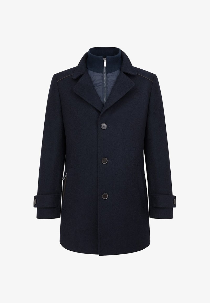 Granatowy wełniany płaszcz z klapami, z przodem zapinanym na pięć guzików oraz bocznymi kieszeniami. Posiada pikowaną podszewkę zapinaną na zamek dla dodatkowego ciepła.