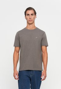 Grå bomull T-skjorte med korte ermer, rund nakke og en liten logo p�å brystet. Kombinert med blå denim jeans.